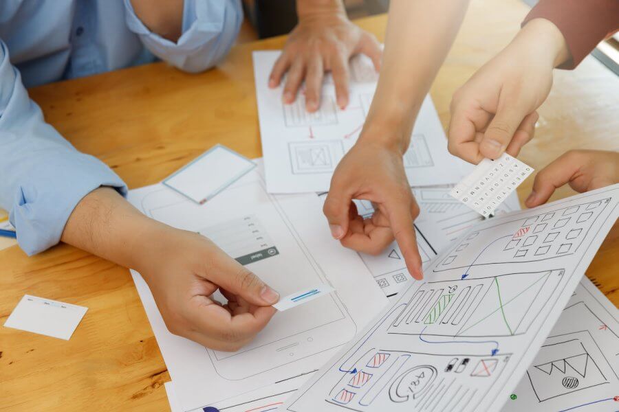 Website wireframes on a desk with hands holding them